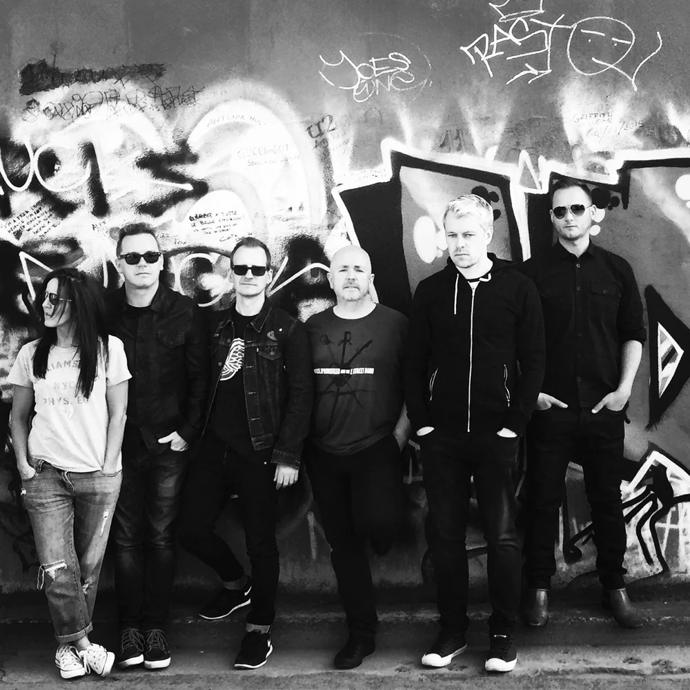 December band members standing together in front of a mural.