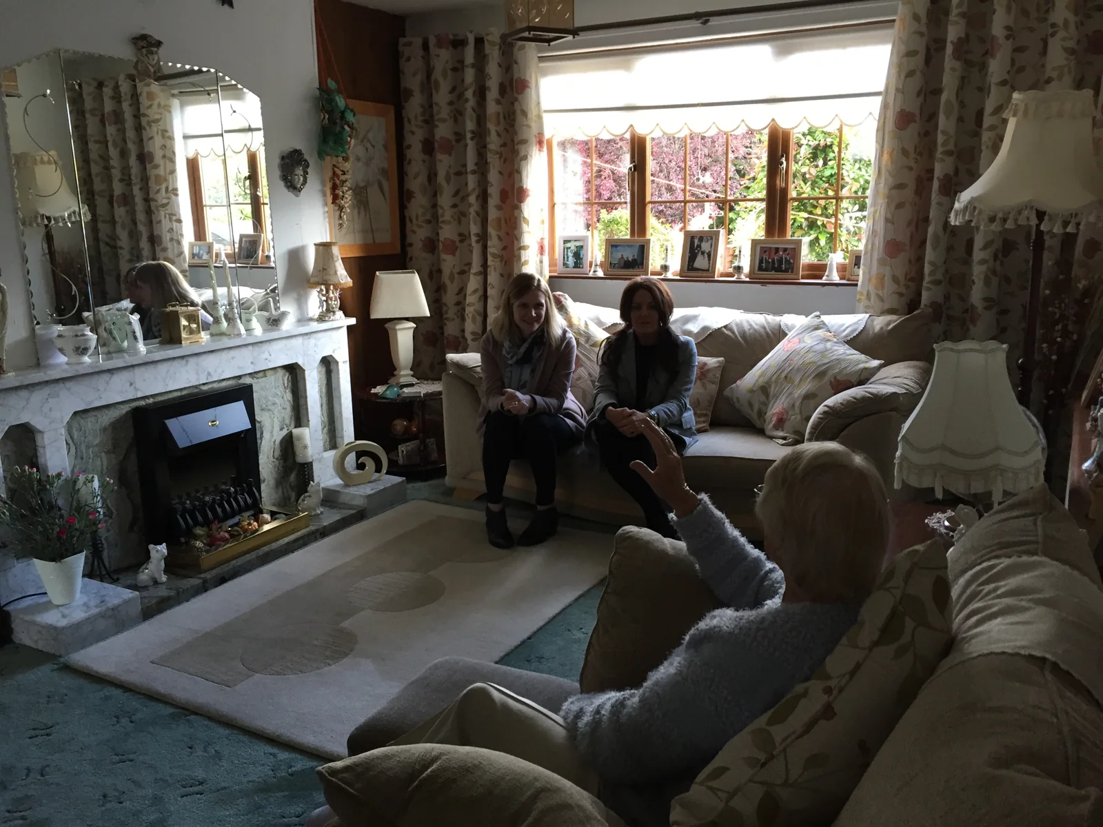 People sitting together in the living room, with a camera held in the foreground.